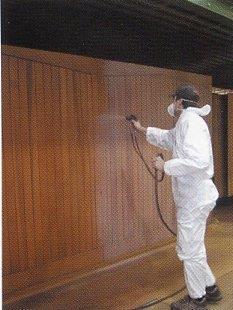 Photo of a sprayer applying an optional fully finished top coat in a woodstain colour. 