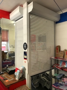 V1: Aluroll security shutters with perforated aluminium laths and full box enclosures.